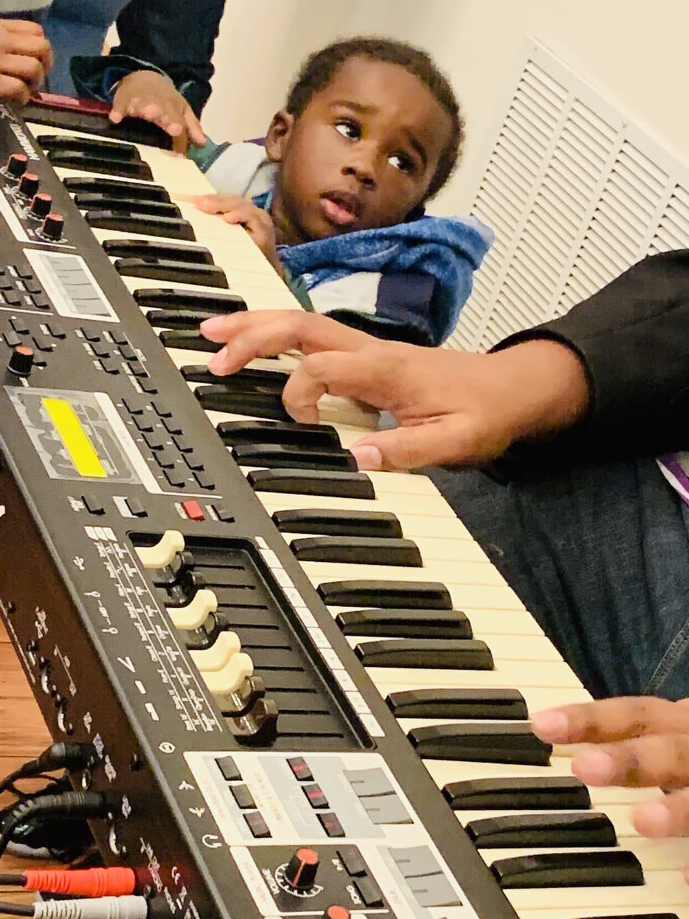 A child reaching to play the keyboard during rehearsal